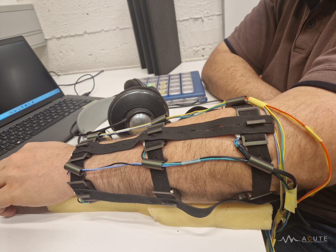 Wearable vibrotactile sleeve worn on the forearm, featuring nine embedded actuators arranged in a 3 × 3 grid and secured with adjustable straps.